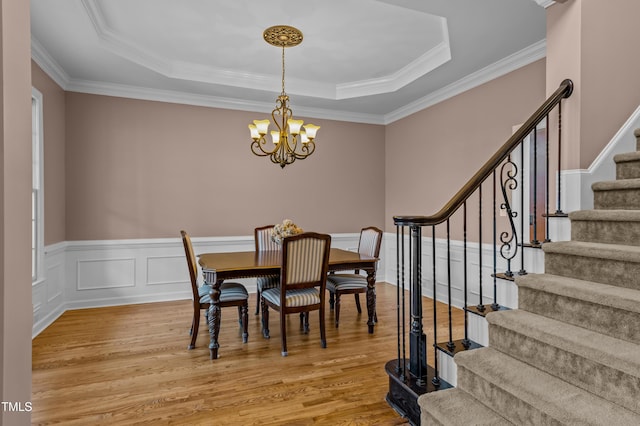 dining space featuring a chandelier, a tray ceiling, and light wood-style floors