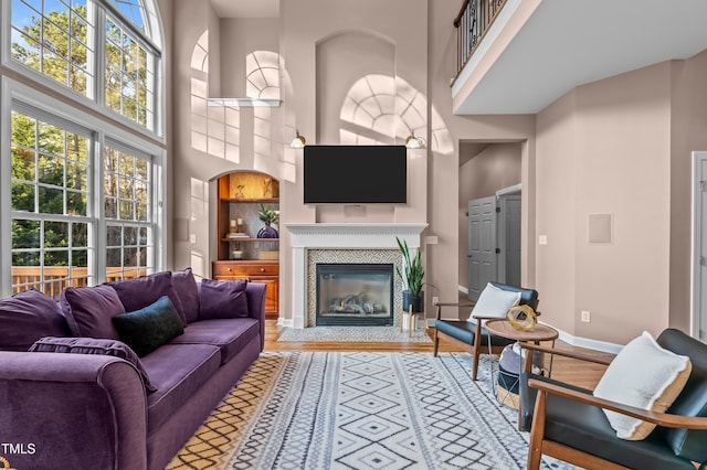 living area featuring a healthy amount of sunlight, light wood-type flooring, baseboards, and a tile fireplace