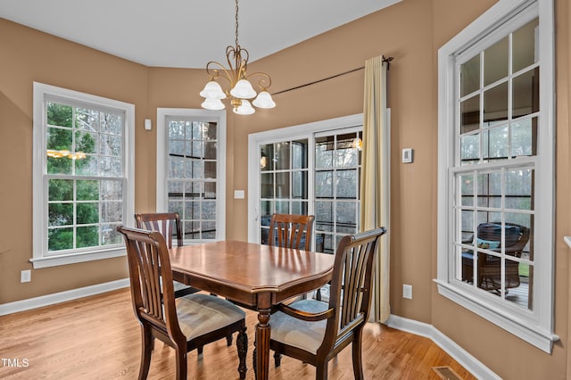 dining room with light wood-type flooring, visible vents, baseboards, and an inviting chandelier