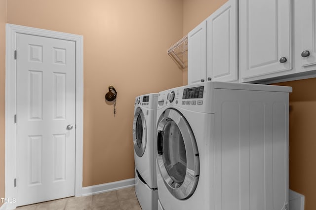 clothes washing area with light tile patterned floors, independent washer and dryer, cabinet space, and baseboards