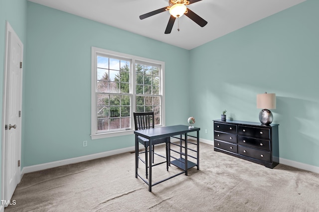 carpeted office space featuring a ceiling fan and baseboards