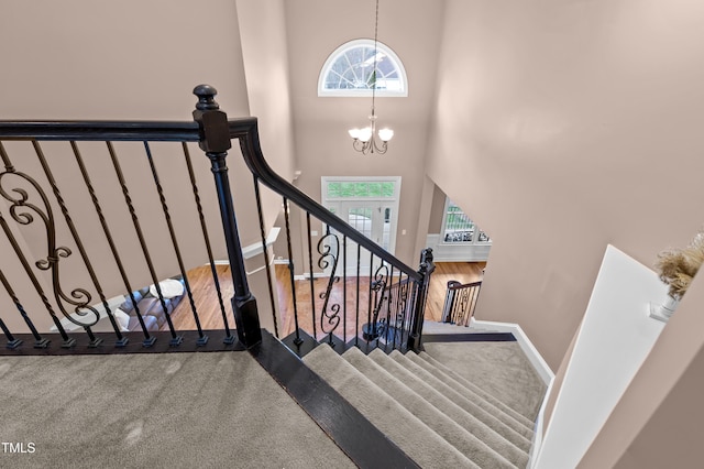 stairs with baseboards, a high ceiling, a wealth of natural light, and a notable chandelier