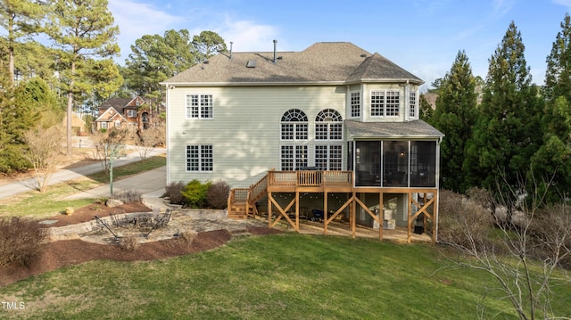 rear view of house featuring a shingled roof, a lawn, a sunroom, stairs, and a wooden deck