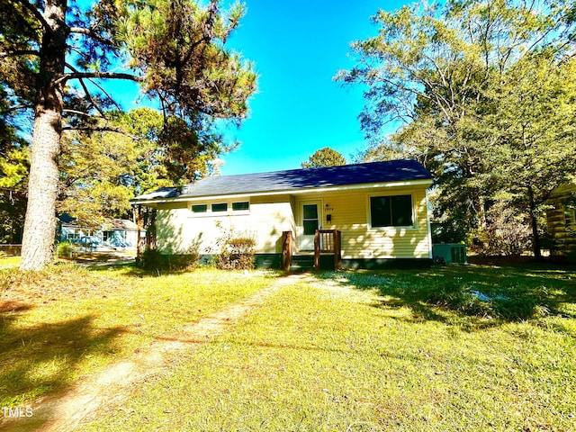 back of house featuring central air condition unit and a lawn