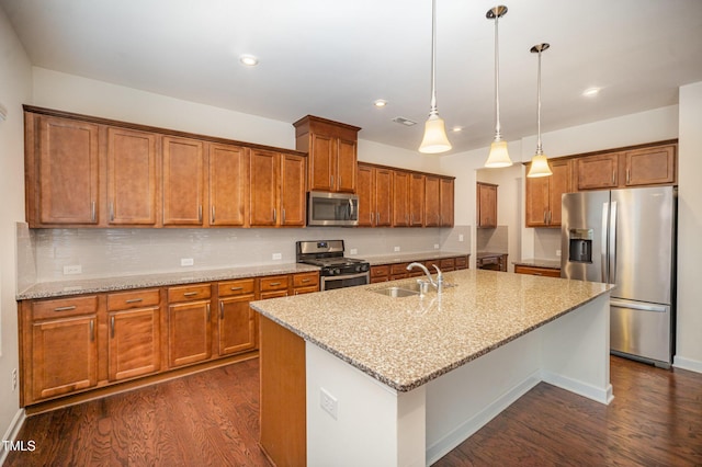 kitchen featuring sink, light stone counters, hanging light fixtures, an island with sink, and stainless steel appliances