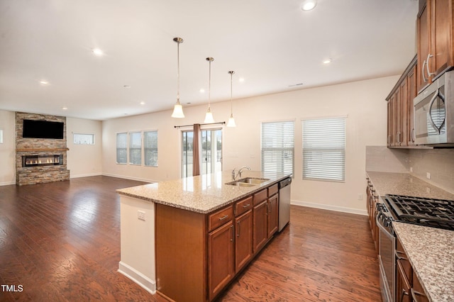 kitchen featuring appliances with stainless steel finishes, decorative light fixtures, tasteful backsplash, an island with sink, and sink