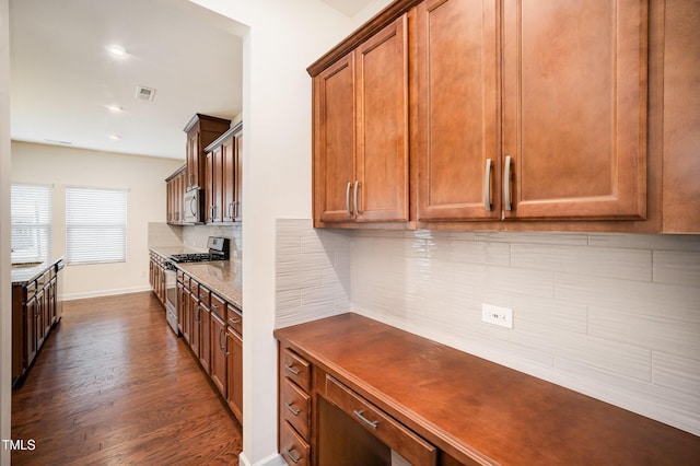 kitchen with appliances with stainless steel finishes, dark hardwood / wood-style flooring, and decorative backsplash