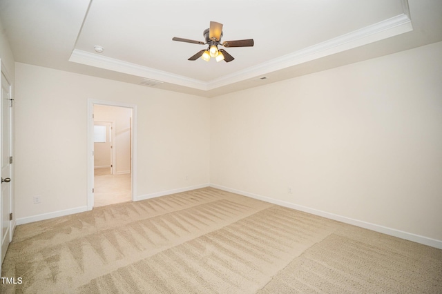 empty room with ornamental molding, light carpet, and a tray ceiling