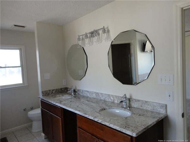 bathroom featuring tile patterned floors, vanity, toilet, and a textured ceiling