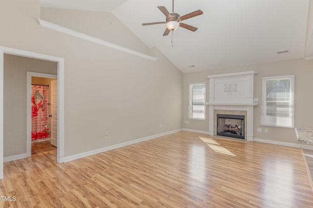 unfurnished living room with a tiled fireplace, ceiling fan, high vaulted ceiling, and light hardwood / wood-style floors