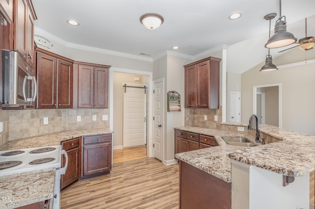 kitchen with sink, tasteful backsplash, decorative light fixtures, kitchen peninsula, and a barn door