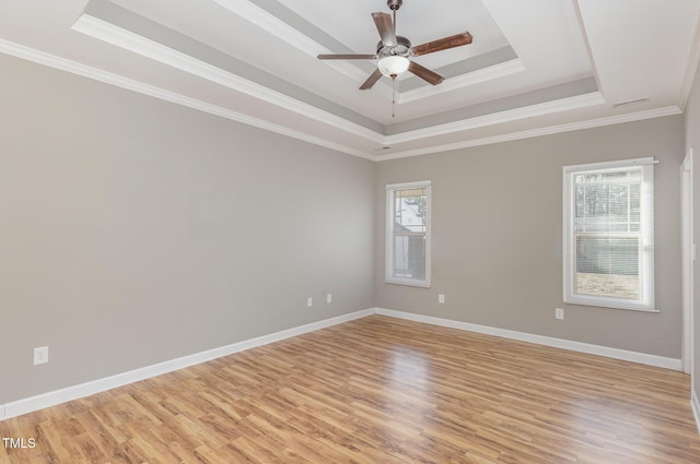 spare room featuring a tray ceiling, ornamental molding, ceiling fan, and light wood-type flooring