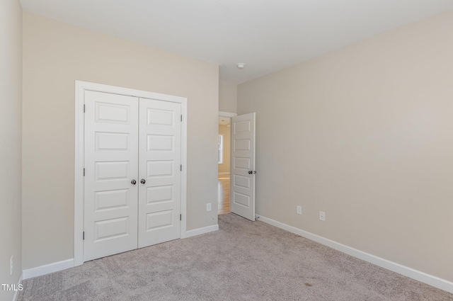 unfurnished bedroom with light colored carpet and a closet