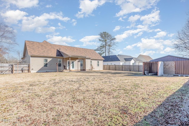 back of property featuring a storage unit and a lawn