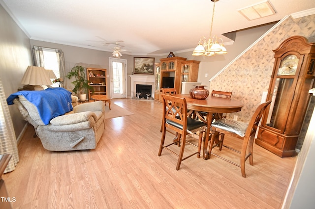 dining area with ornamental molding, ceiling fan with notable chandelier, and light hardwood / wood-style flooring