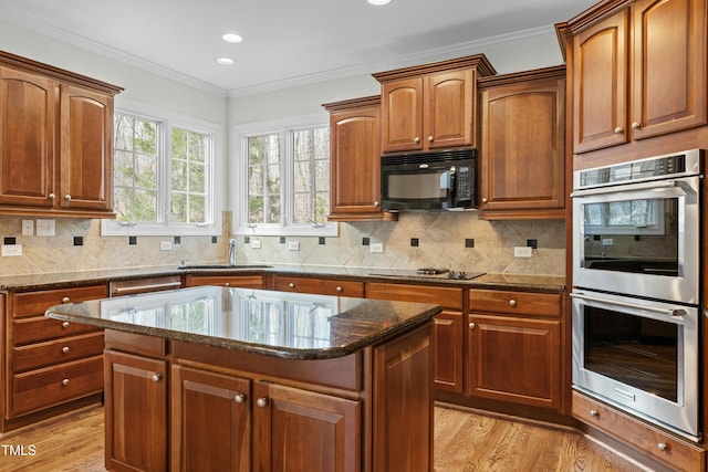 kitchen featuring light wood-type flooring, black appliances, a sink, dark stone counters, and crown molding