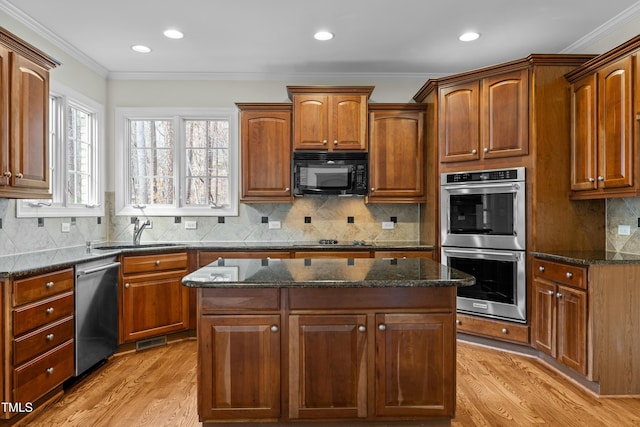 kitchen featuring black appliances, crown molding, a kitchen island, and a sink