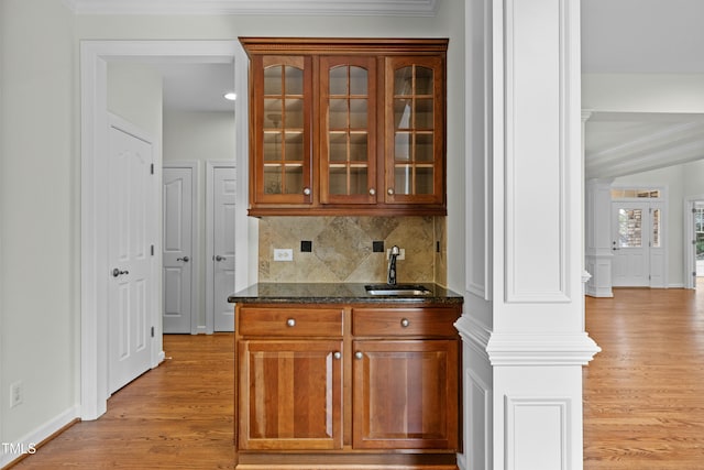 bar featuring crown molding, light wood-type flooring, backsplash, and a sink