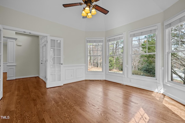 unfurnished sunroom featuring ornate columns, vaulted ceiling, a ceiling fan, and a wealth of natural light