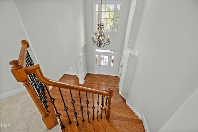 foyer featuring wood finished floors, stairway, a high ceiling, baseboards, and a chandelier