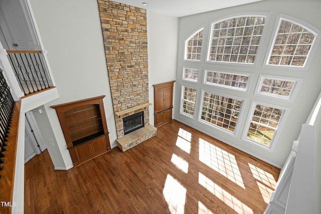 living area featuring dark wood-style floors, a fireplace, a high ceiling, and a wealth of natural light