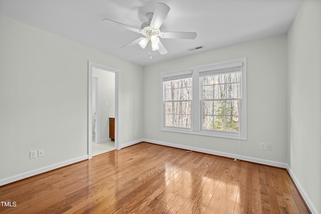 spare room featuring visible vents, a ceiling fan, baseboards, and hardwood / wood-style floors