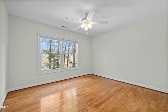 unfurnished room with hardwood / wood-style floors, baseboards, visible vents, and ceiling fan