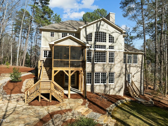 rear view of house featuring stairway, a chimney, a patio, and a sunroom