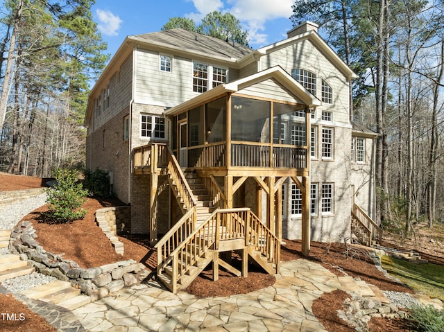 view of front facade with stairway, brick siding, and a sunroom