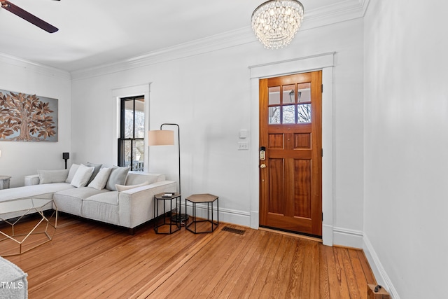 interior space with baseboards, crown molding, visible vents, and light wood finished floors