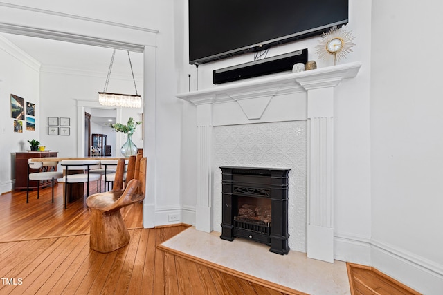 room details with ornamental molding, baseboards, a tiled fireplace, and wood finished floors