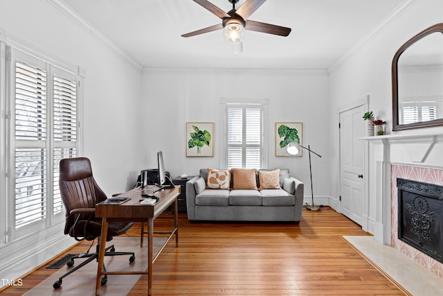 office featuring ornamental molding, a fireplace with flush hearth, a ceiling fan, and light wood-style floors