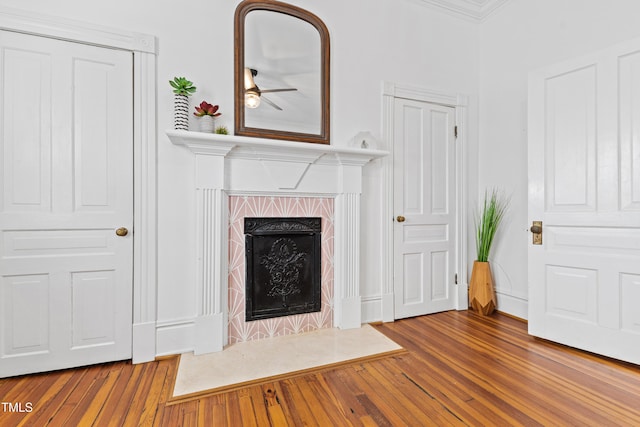 unfurnished living room with ornamental molding, a high end fireplace, baseboards, and wood finished floors