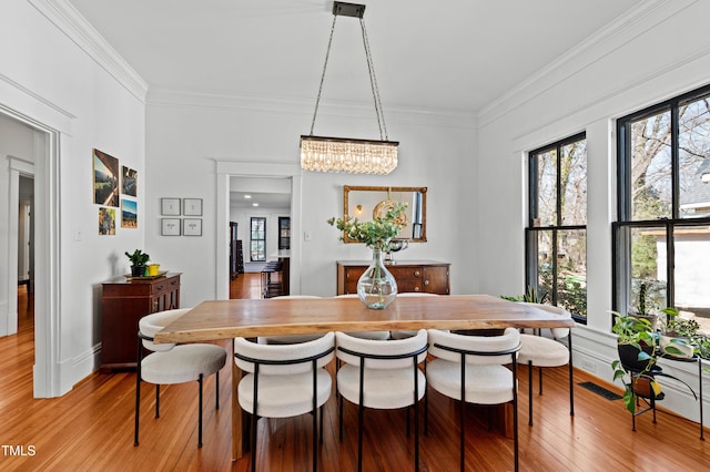 dining room featuring a chandelier, visible vents, crown molding, and light wood-style flooring