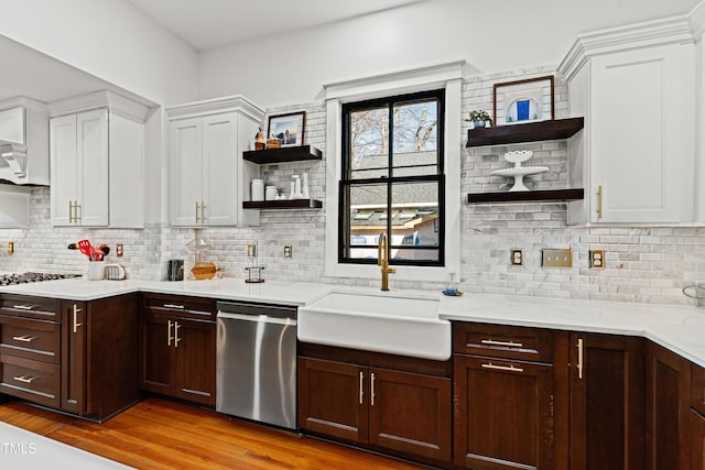 kitchen featuring open shelves, light countertops, white cabinetry, a sink, and dishwasher