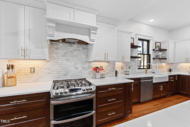 kitchen featuring white cabinets, appliances with stainless steel finishes, light countertops, open shelves, and a sink