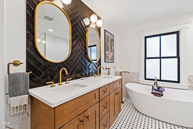 bathroom featuring visible vents, a sink, tile walls, and a freestanding bath