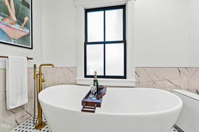 full bathroom featuring wainscoting, a freestanding tub, and tile walls