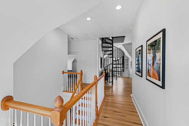 corridor with light wood-style floors, recessed lighting, baseboards, and an upstairs landing