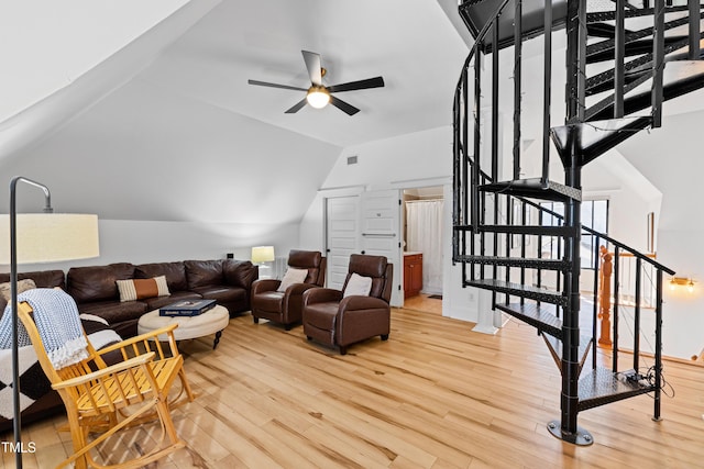 living area with lofted ceiling, light wood-style floors, stairway, and a ceiling fan