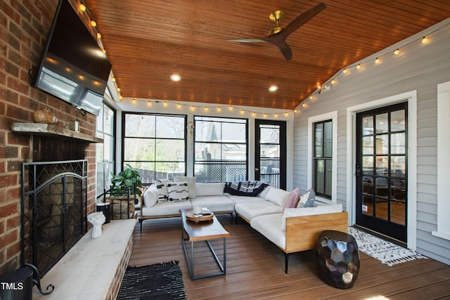 sunroom with lofted ceiling, ceiling fan, an outdoor brick fireplace, and wood ceiling