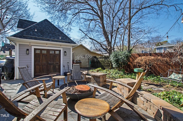 view of patio featuring an outdoor fire pit, fence, and an outdoor structure