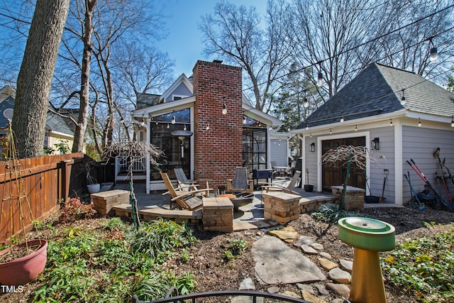 back of property featuring an outdoor fire pit, an outdoor structure, fence, a sunroom, and a chimney