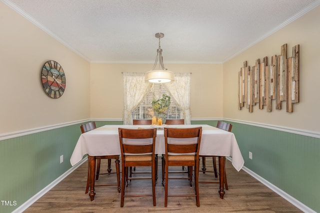 dining room with wood-type flooring, ornamental molding, and a textured ceiling