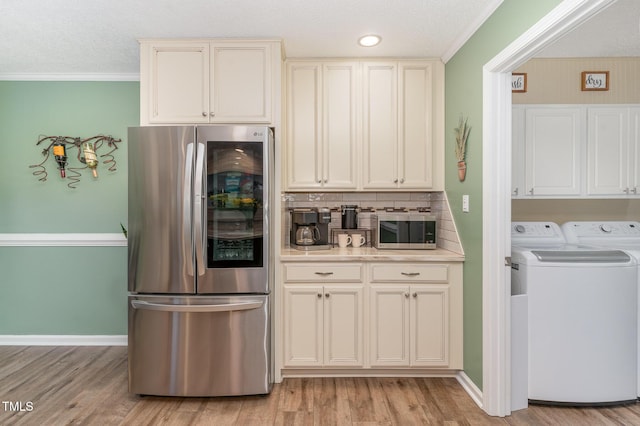 kitchen with crown molding, light hardwood / wood-style flooring, appliances with stainless steel finishes, washer and dryer, and decorative backsplash