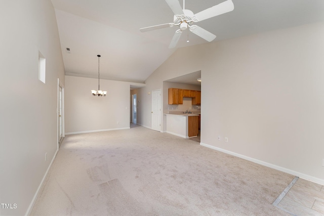 unfurnished living room with high vaulted ceiling, ceiling fan with notable chandelier, and light colored carpet