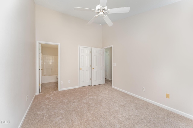 unfurnished bedroom with connected bathroom, high vaulted ceiling, and light carpet