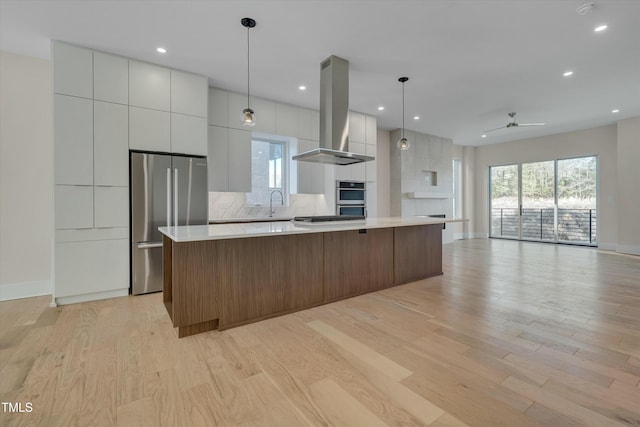 kitchen with island range hood, decorative light fixtures, stainless steel appliances, a large island, and decorative backsplash