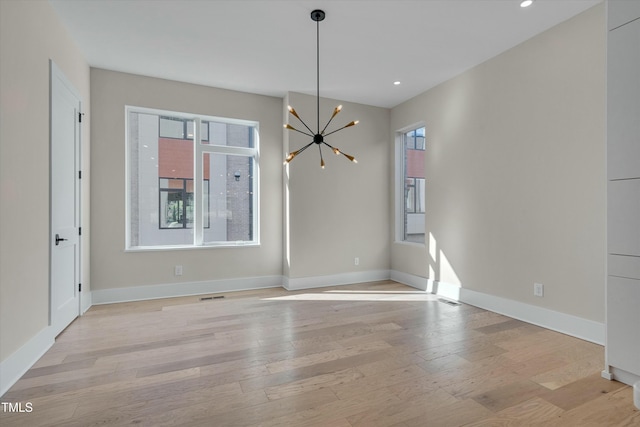 unfurnished dining area with an inviting chandelier, light hardwood / wood-style floors, and a wealth of natural light