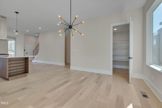 living room featuring built in shelves, a chandelier, and light hardwood / wood-style flooring